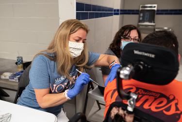 McKinney ISD registered nurse Stephanie Martin administers a COVID-19 vaccine to a 17-year-old at the McKinney ISD Stadium and Community Event Center on May 20, 2021.