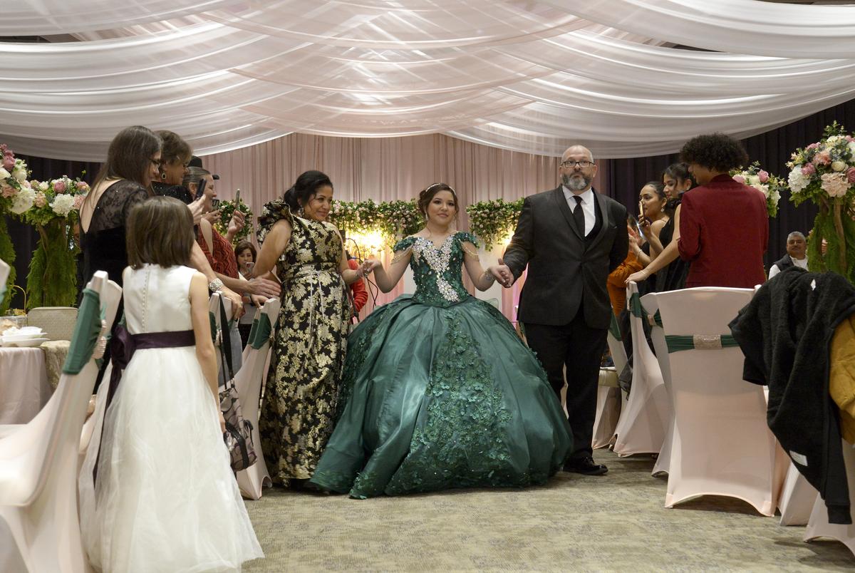 Guest stand and applaud as Sienna Raley, flanked by her parents Maria and Troy, begins the Grand Entrance at her Quincenera Saturday, December 16, 2023, in Didoll, Texas.