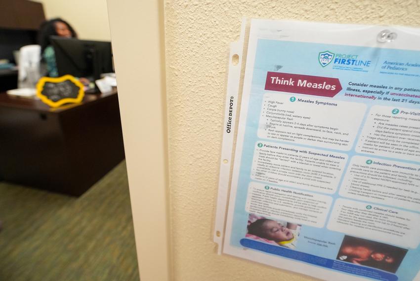A sign donning measles information is posted outside of the office of Dr. Rumbidzai Mutikani, a pediatrician at the Hobbs Medical Clinic, as she works at her desk Monday, Feb. 24, 2025, in Hobbs, N.M.