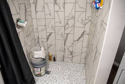 Buckets sit inside a non-functioning shower inside the home of Christine Lopez in Friendswood on Tuesday, Dec. 10, 2019. The buckets are used to fill with hot water that the family then uses to shower. The home was severely damaged by flood water as a result of Hurricane Harvey in 2017.