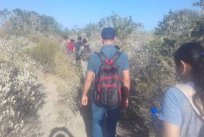 Nicaraguan migrant Grisber Calero, carrying a red and black backback, walks along a trail near the highway between Monterrey and Reynosa, Mexico, in order to avoid a law enforcement checkpoint in August 2018.