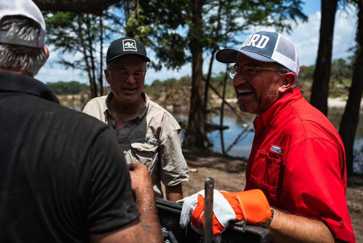 Cord Shiflet, right, jokes with volunteers while aiding in cleanup and recovery efforts at Camp CAMP, a summer camp for people with disabilities by Children's Association for Maximum Potential, following the Kerr County flood on Friday, July 11, 2025, in Center Point.