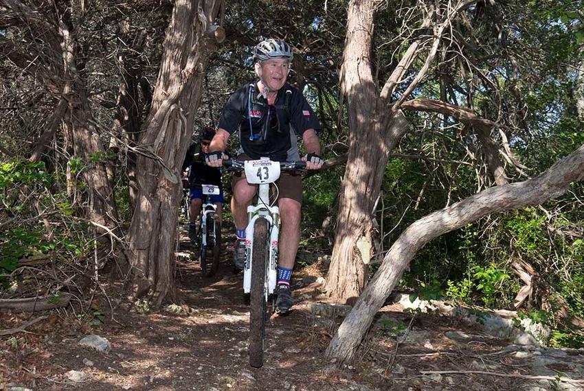 Former President Bush leads the way through a stand of cedar trees on his ranch near Crawford during his annual W100K ride for wounded veterans on May 1, 2015.