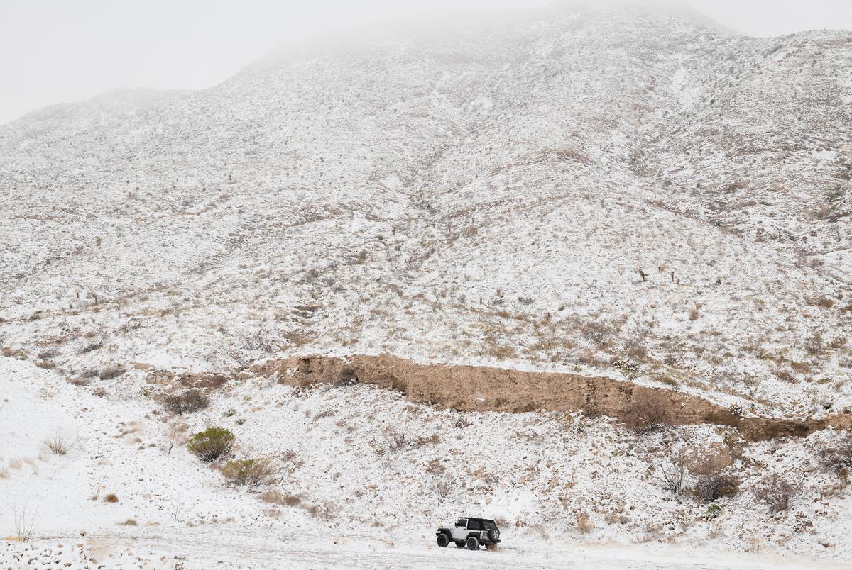 A Jeep drives offroad beneath the snow covered Franklin Mountains in El Paso, Texas on February 15, 2021.