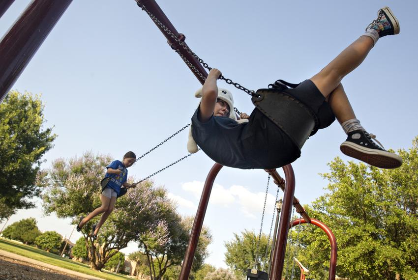 Halo Turner and her younger sister Annabelle see who can swing the highest at Crescent Park in Frisco on June 23, 2021.