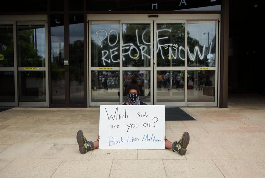 A protester sits outside an entrance to City Hall in Austin on May 31, 2020.