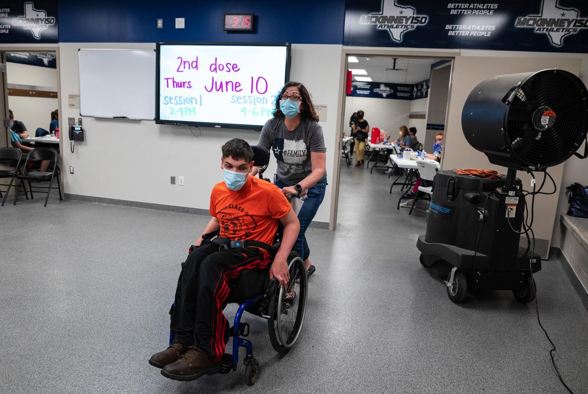 Joshua Martin, 17, is pushed by his mother Teddi Martin after they received their first dose of a COVID-19 vaccine at McKinney ISD Stadium and Community Event Center on May 20, 2021.