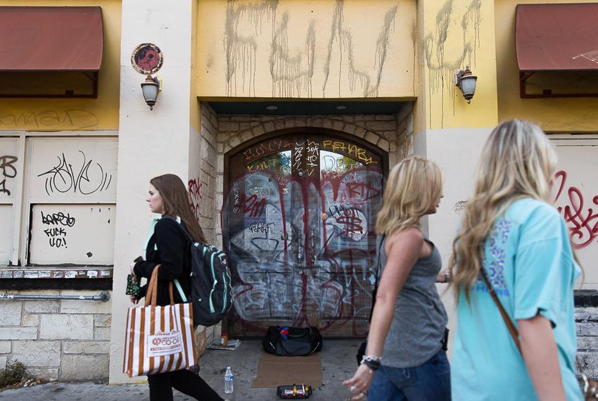 Students walk past a heavily graffitied building that once was Mellow Mushroom on Guadalupe Street next to the University of Texas campus on April 9, 2016.