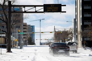 Vehicles attempt to drive uphill through snow and ice on Guadalupe Street in Austin, Feb. 15, 2021.