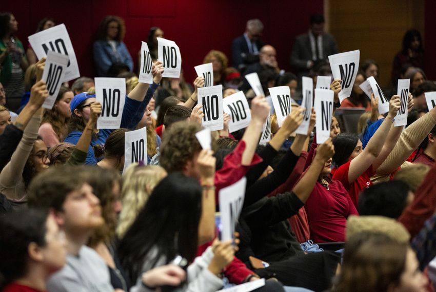 Students raise papers printed "NO," disagreeing with a panelist's answers during the Open Dialogue with UT Leadership about Sexual Misconduct Policies & Practices on Monday.