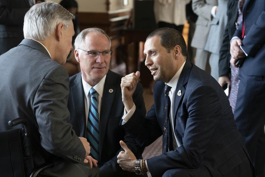 Gov. Greg Abbott talks with state Reps. Kyle Biedermann, R-Fredricksburg, left, and Poncho Nevárez, D-Eagle Pass, on the House floor in Austin on March 27, 2019.