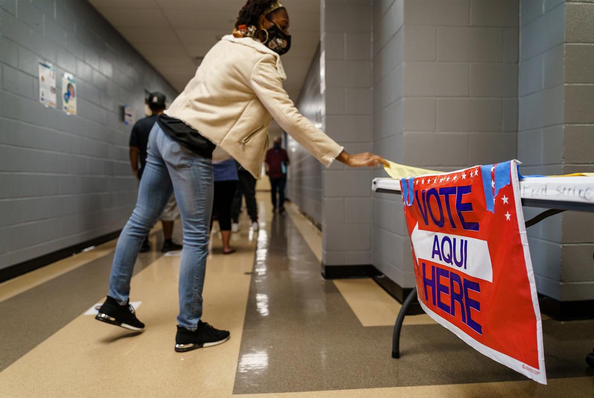 A voter picks up a copy of the ballot while they wait in line to vote at a polling location in Manor on Election Day. Nov. 3, 2020.