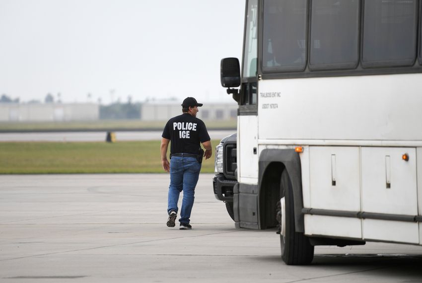 A law enforcement official walks past a transport bus used to carry migrants in U.S. Immigration and Customs Enforcement custody.