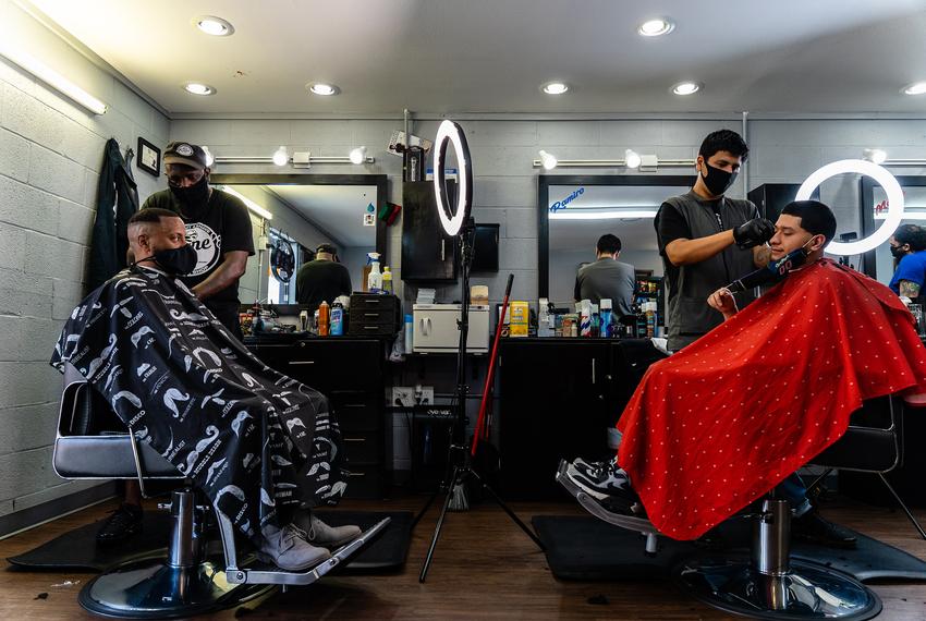 Stevin Kane and Ramiro Cruz give haircuts to customers, after Kane's Barbershop reopened from being closed due to the coronavirus pandemic.