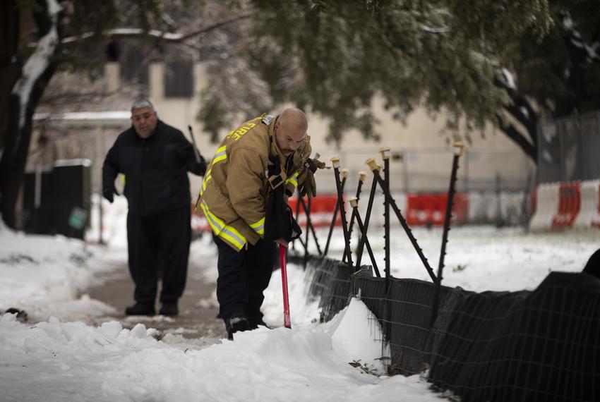 Firefighters clear snow and ice from a side walk outside of the Rebekah Baines Johnson Center in East Austin on Feb. 17, 2021. Elderly residents were evacuated because of a power outage.