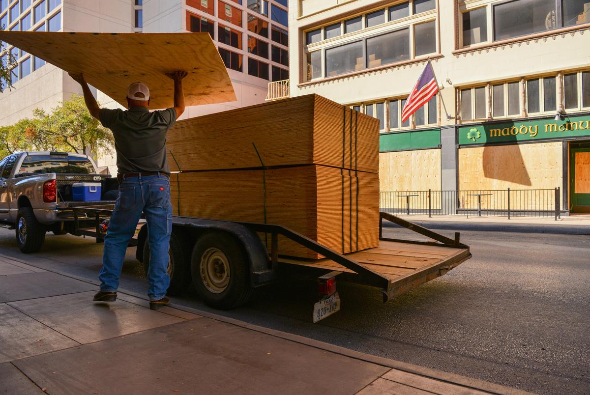 A worker unloads sheets of plywood to board up a downtown San Antonio building in the event of civil unrest as a result of the election.