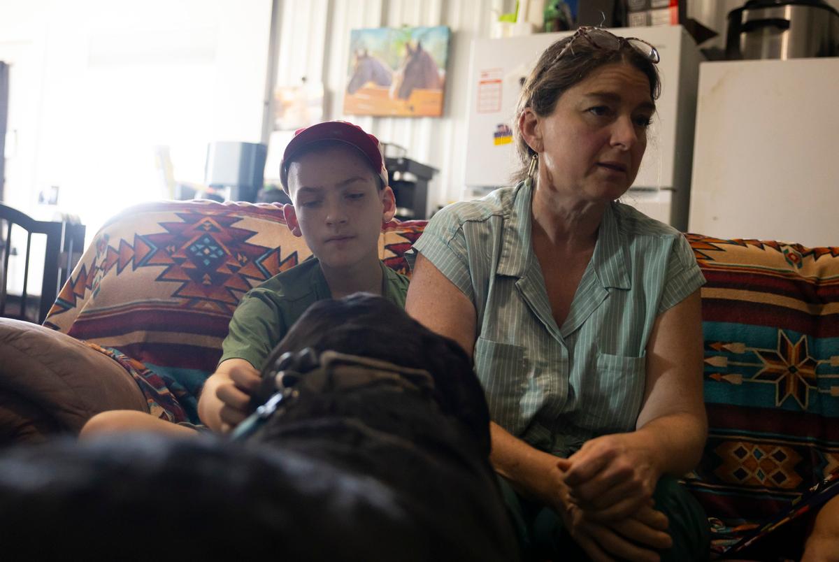Zach Lindeen pets Ruger, one of Romana Harding’s dogs, as his listens to his mom speak about how cannabis quiets his seizures during an interview on Tuesday, July 29, 2025, outside of Midway, TX.