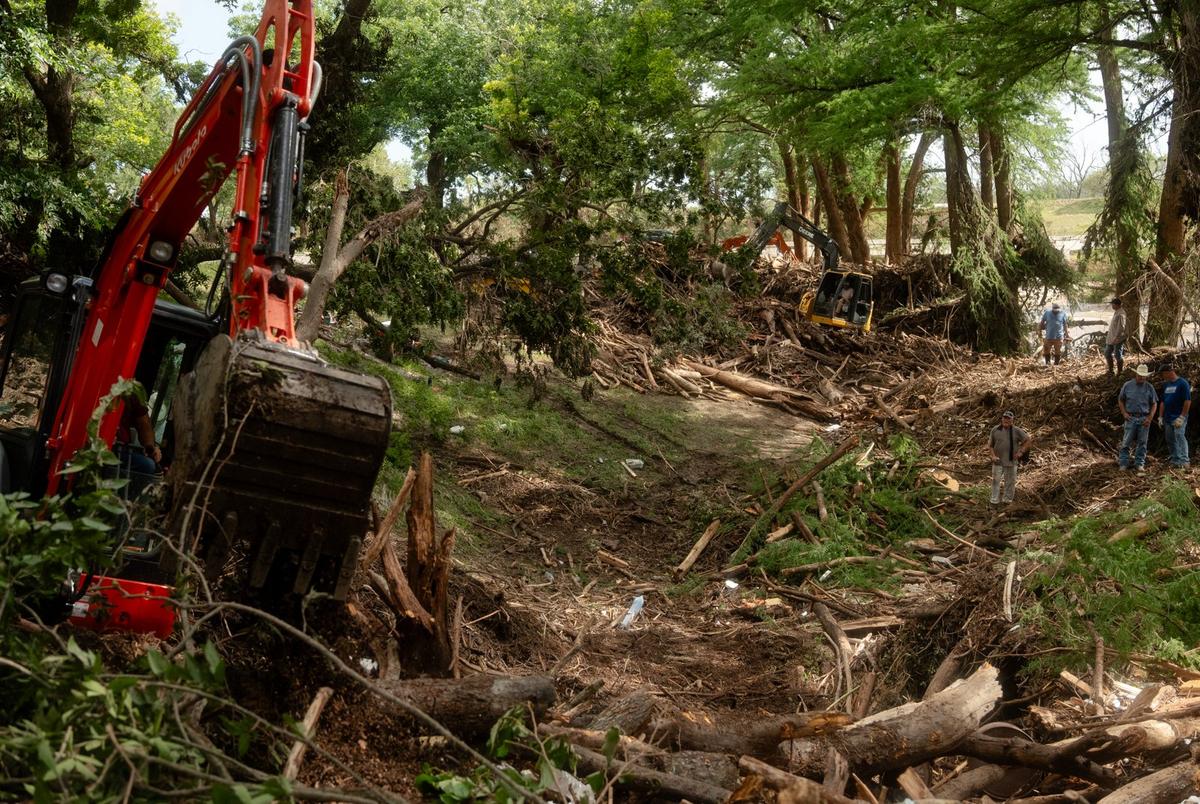 Law enforcement officials and volunteers clear up mountains of debris deposited by the flood in Center Point on Tuesday July 8, 2025.
