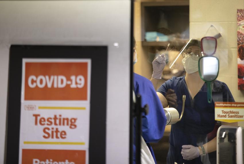 A nurse demonstrates to a student how to self-administer a COVID-19 test a at a testing location at the University of Texas …