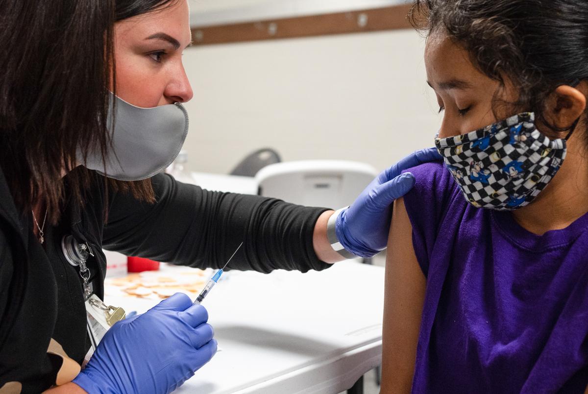 McKinney ISD registered nurse Jennifer Beaverson, left, administers a COVID-19 vaccine to Rory Augustin, 15, at McKinney ISD Stadium and Community Event Center on May 20, 2021.