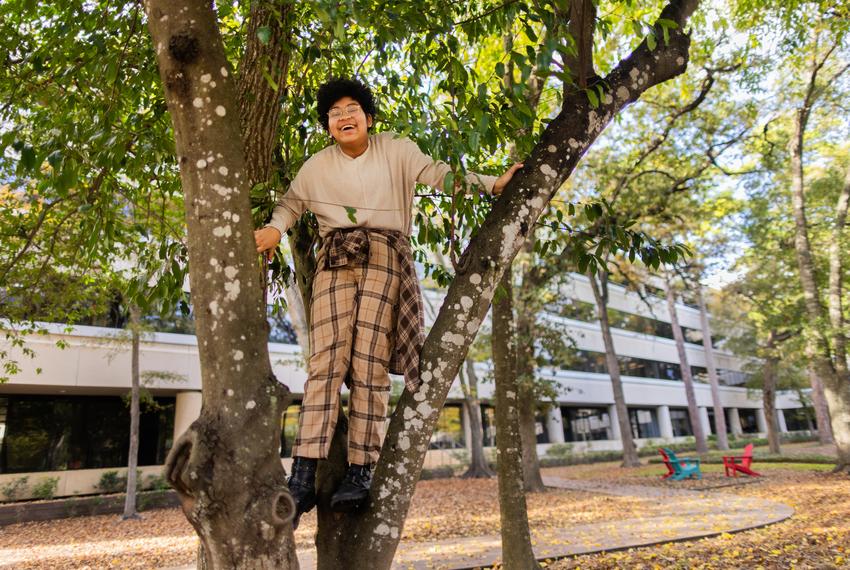 Former Mayde Creek High School student Kadence Carter, 17, is all smiles as he playfully climbs a tree while spending time at his father's workplace on Dec. 8, 2023, in Houston.