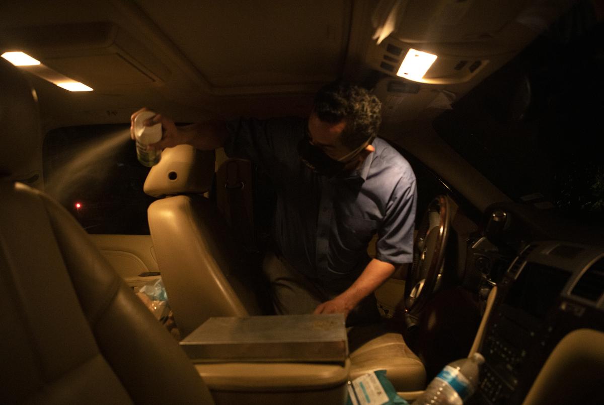 Juan Lopez sprays disinfectant after placing a body in the interior of his vehicle in McAllen. Lopez picks up the bodies of the deceased and delivers them to local funeral homes. July 17, 2020. 