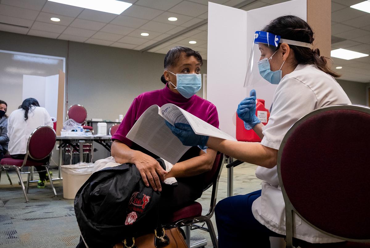 Beverly Mills, a teacher at Anderson Elementary School, speaks to pharmacist Ilana Druker before getting vaccinated at Houston Independent School District’s Hattie Mae White Educational Support Center on January 9, 2021 in Houston. HISD partnered with Kroger to administer the covid-19 Moderna vaccine to educators, police officers and school nurses as part of Phase 1A and 1B of the vaccine rollout. (May-Ying Lam for The Texas Tribune)