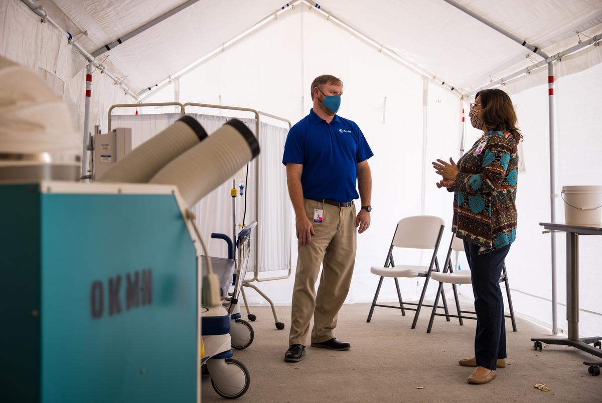 David Lee, Chief Executive Officer, speaks with Barbara James inside a tent set aside for triaging COVID-19 patients located just outside the ER ambulance bay at Otto Kaiser Memorial Hospital in Kenedy.