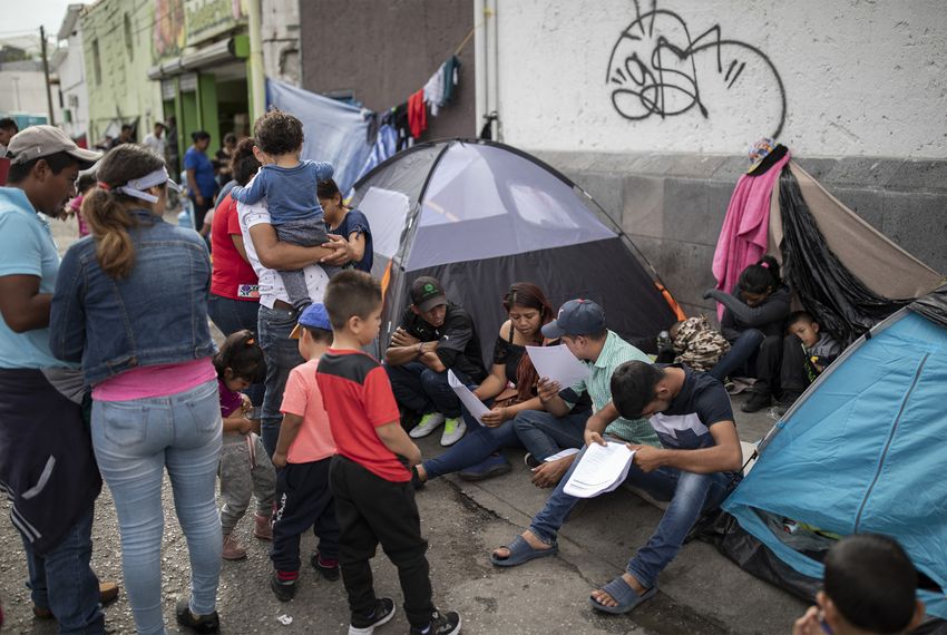 Migrants look over their documents at a makeshift migrant camp at the base of the Paso del Norte International Bridge in Ciudad Juárez on Oct. 3. Migrants wait close to the port of entry so they won't lose their spot in line to legally cross into the U.S. and seek asylum.