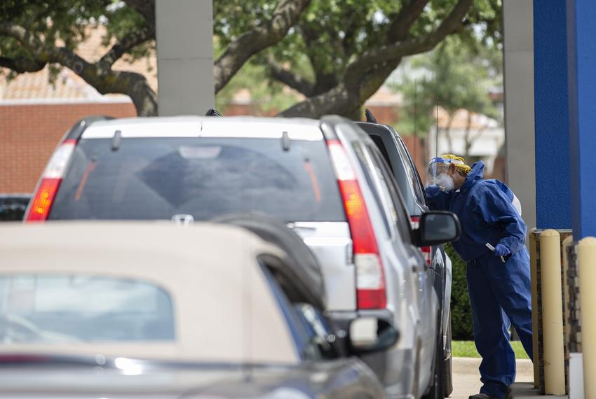 A health care worker administers a coronavirus test on a patient at a drive thru testing site at Exceptional Medical Plaza in Garland on June 30.