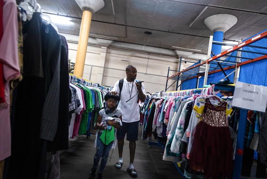 Billy Peck, 34, and his daughter look through donated clothing at the Haven for Hope shelter in San Antonio on Nov. 10, 2022. Peck and the other residents of Haven for Hope are welcome to take anything they need or want from the warehouse with donations, as one of the services that the shelter offers.