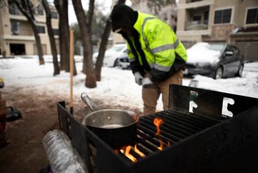Jacob Duran prepares wood for a grill. Duran has been cooking meals outsides after his apartment lost power. Feb. 18, 2021.