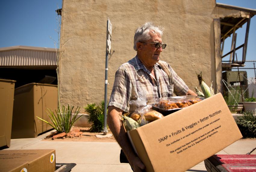 A volunteer loads a box of groceries into a truck for delivery to a nearby community in the the panhandle.