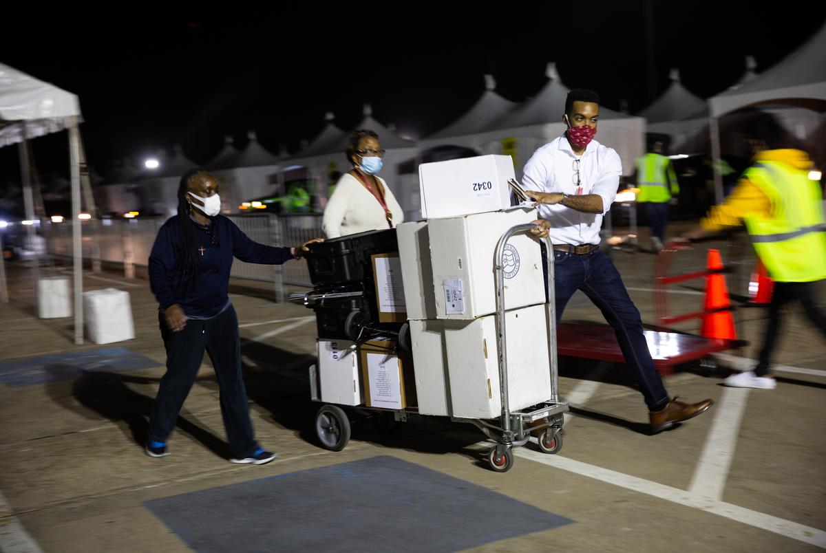 Harris County election workers wheel in polling materials that contain ballot data at the NRG Arena in Houston on Nov. 3, 2020.