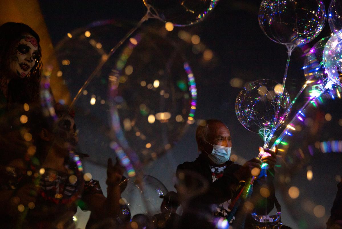 A vendor sells lit up balloons at the Día de los Muertos parade at the Dallas City Hall in Dallas, TX on October 30, 2021.