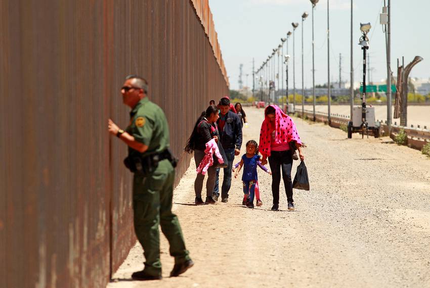Central American migrants walk next to the U.S.-Mexico border fence after crossing into El Paso.