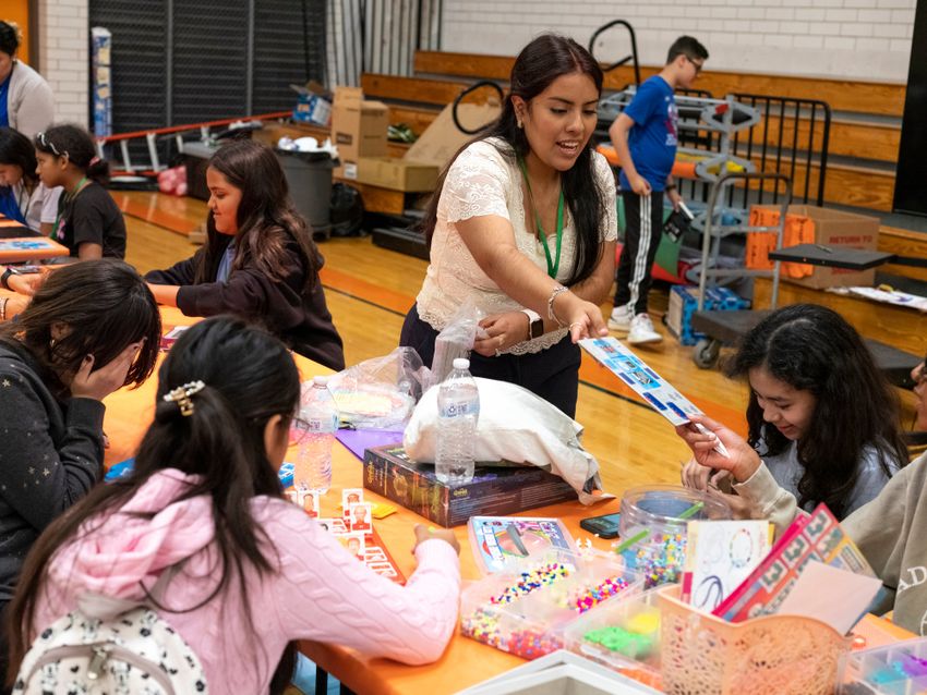 AUSTIN, TEXAS - July 24, 2025: Denisse Badillo, a promoter with Austin Voices, passes out cardboard robots to campers. Austin Voices for Education and Youth hosts a summer camp at the Dobie Middle School for students that attend the three Austin ISD schools at risk of closure. Ilana Panich-Linsman for The Texas Tribune
