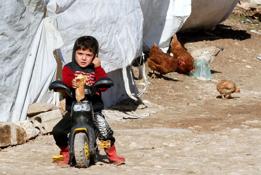 A Syrian refugee boy sits on a bike at a camp in Bar Elias, in the Bekaa Valley, Lebanon.