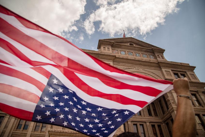 Brendan Cavanagh waves an American flag while participating in a rally in opposition to SB 7 at the state capitol on April 8, 2021.