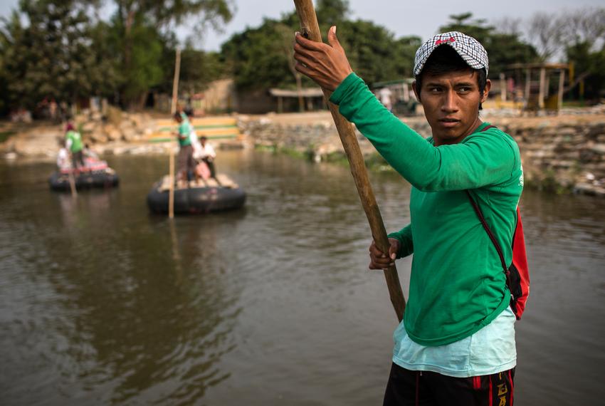 Esvin Lopez, 19, a raft conductor who works ferrying people and goods across the Suchiates River separating Ciudad Hidalgo, Mexico, and Tecun Uman, Guatemala, uses a long wooden pole to propel the raft from one side of the river to the other.