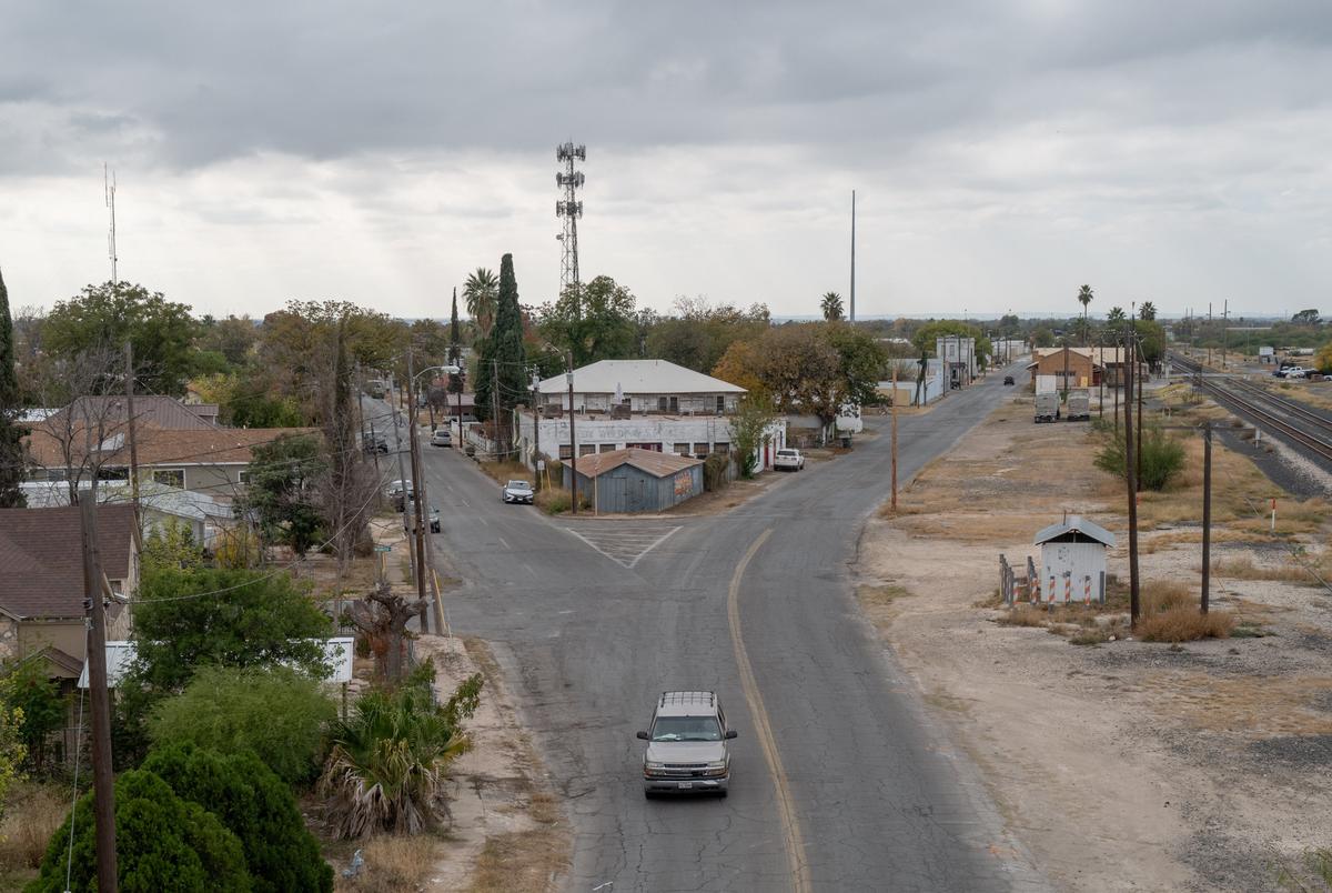 A car drives through a Y intersection in an area with a few scattered houses.