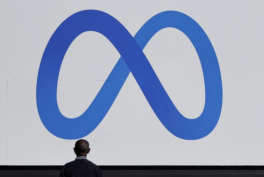 A man stands in front of a sign of Meta, the new name for the company formerly known as Facebook, at its headquarters in Menlo Park, California, on Oct. 28, 2021.