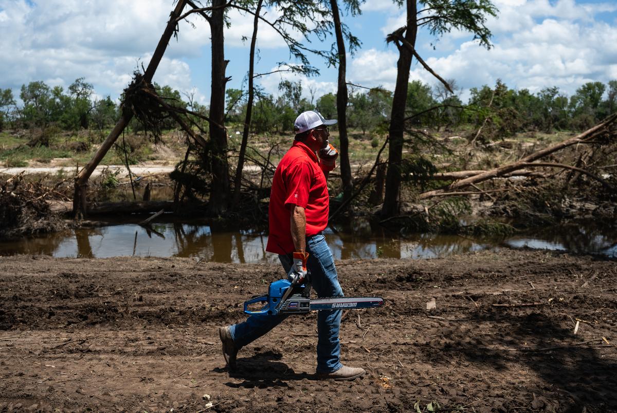 Cord Shiflet carries a chainsaw to assist in cleanup and recovery efforts at Camp CAMP, a special needs summer camp organized by Children's Association for Maximum Potential, Friday, July 11, 2025, in Center Point. On Wednesday, July 9, Shiflet made a post on Facebook calling for volunteers to help clean up Camp CAMP in time before the next session of summer camp starts on Sunday, July 13. Since the post has been published, over 7,000 people have shared his call for help and over 1,000 volunteers have given their time and equipment to the effort.