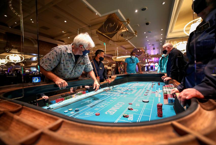 Gene Koonce plays on a craps table fitted with protective plexiglass panels during the reopening of Bellagio hotel-casino, closed since March because of COVID-19. Las Vegas, Nevada on June 4, 2020.