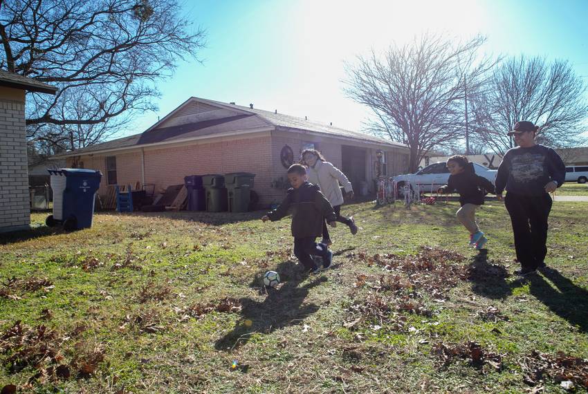 Frances Sanchez plays soccer with her three children, Pedro (left), Katrina and Samaria in the front yard of a friend's house where they are staying.