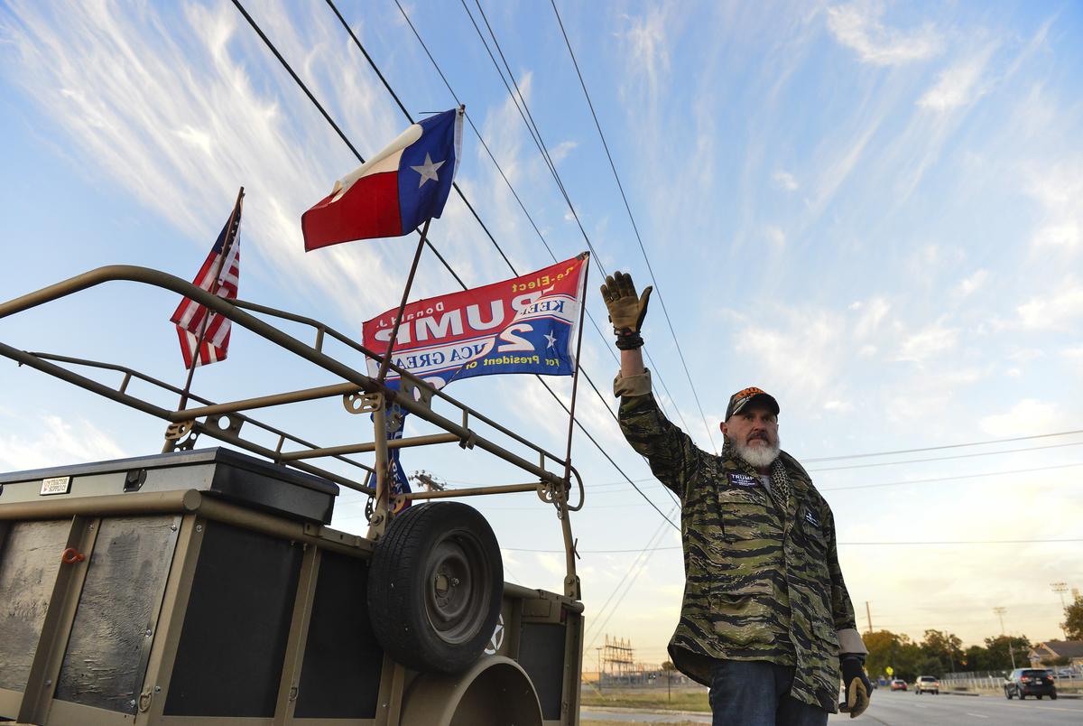 Kevin Rury waves to cars across from the polling station in Schertz early on Election Day morning.