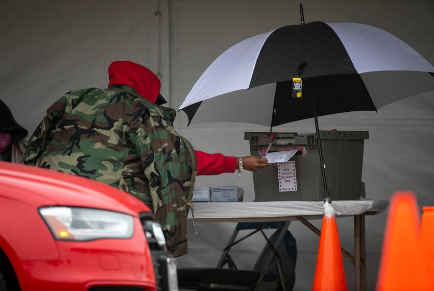 An election worker submits a mail-in ballot at the Harris County ballot drop-off site at NRG Stadium in Houston on Wednesday, Oct. 28, 2020.