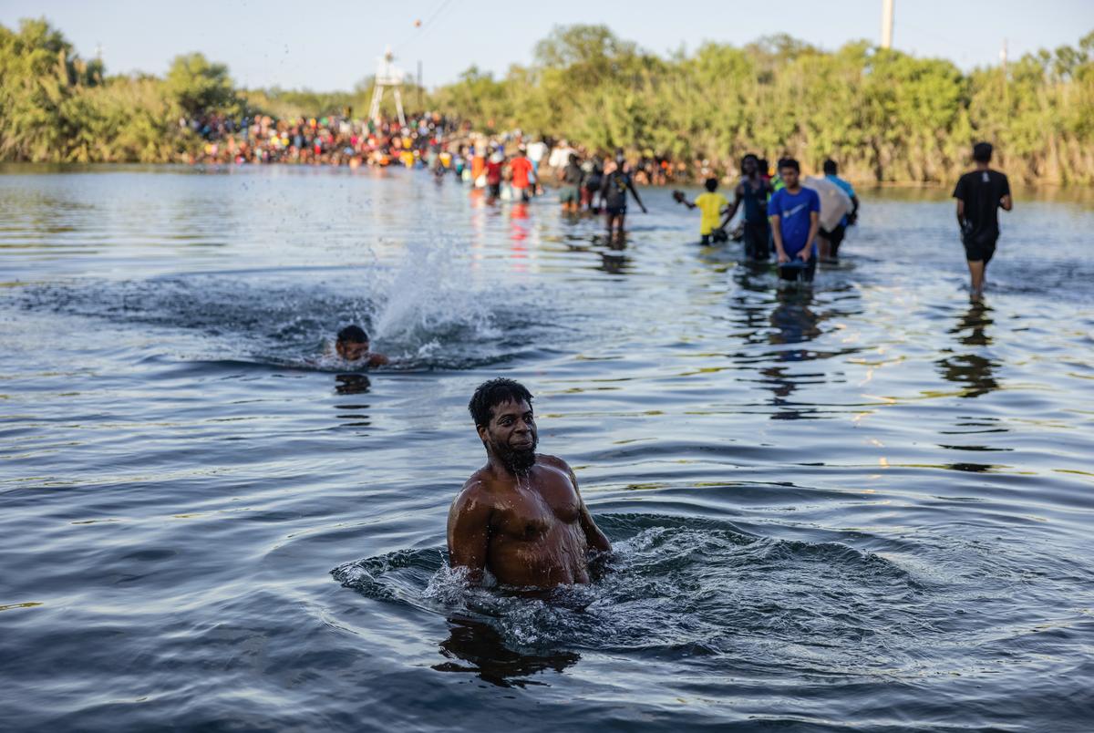 Migrants cross the Rio Grande with food, water, shelter, clothing, and other supplies as they prepare to spend the night under the International Bridge in Del Rio on September 16, 2021.