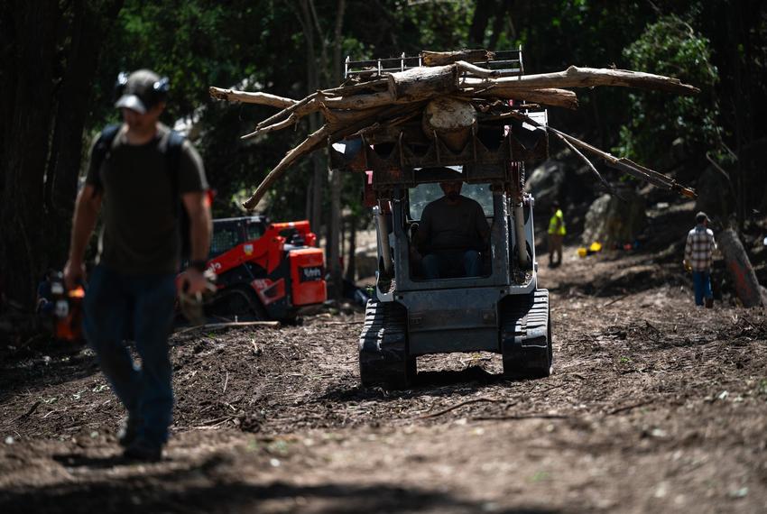 A volunteer driving a bobcat moves flood debris to pile intended to be chipped while assisting in recovery efforts at Camp CAMP, a special needs summer camp organized by Children's Association for Maximum Potential, Friday, July 11, 2025, in Center Point.