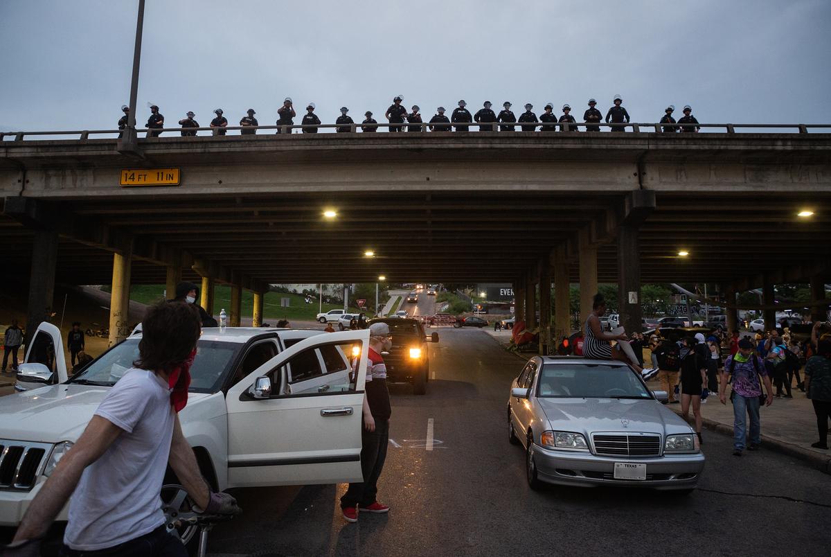 Austin Police officers watch a crowd of protestors near their police headquarters in May. 